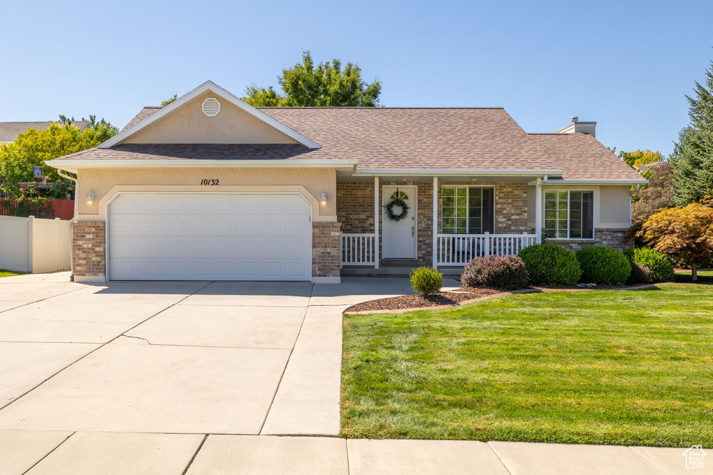 Ranch-style home featuring a garage, a front yard, and a porch