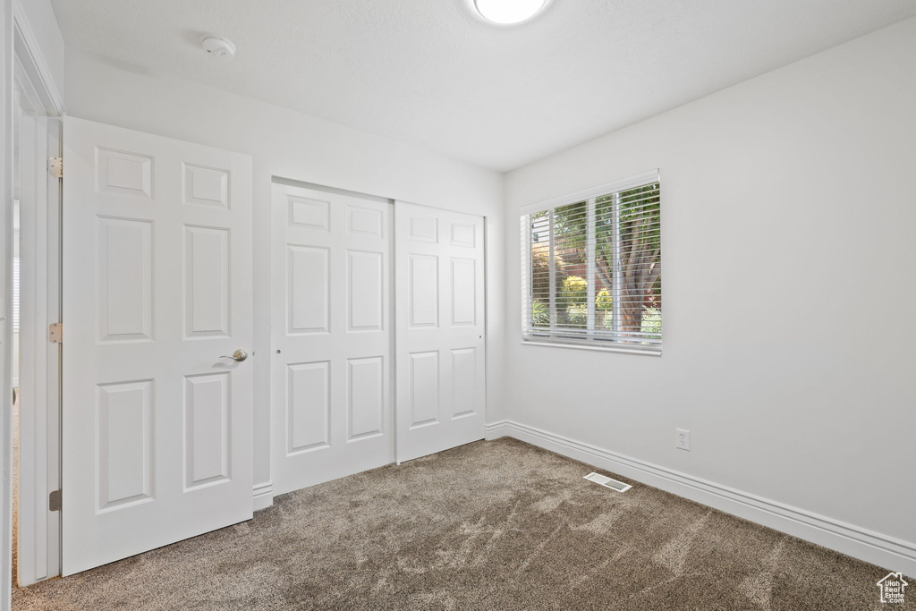 Unfurnished bedroom with a closet and carpet flooring