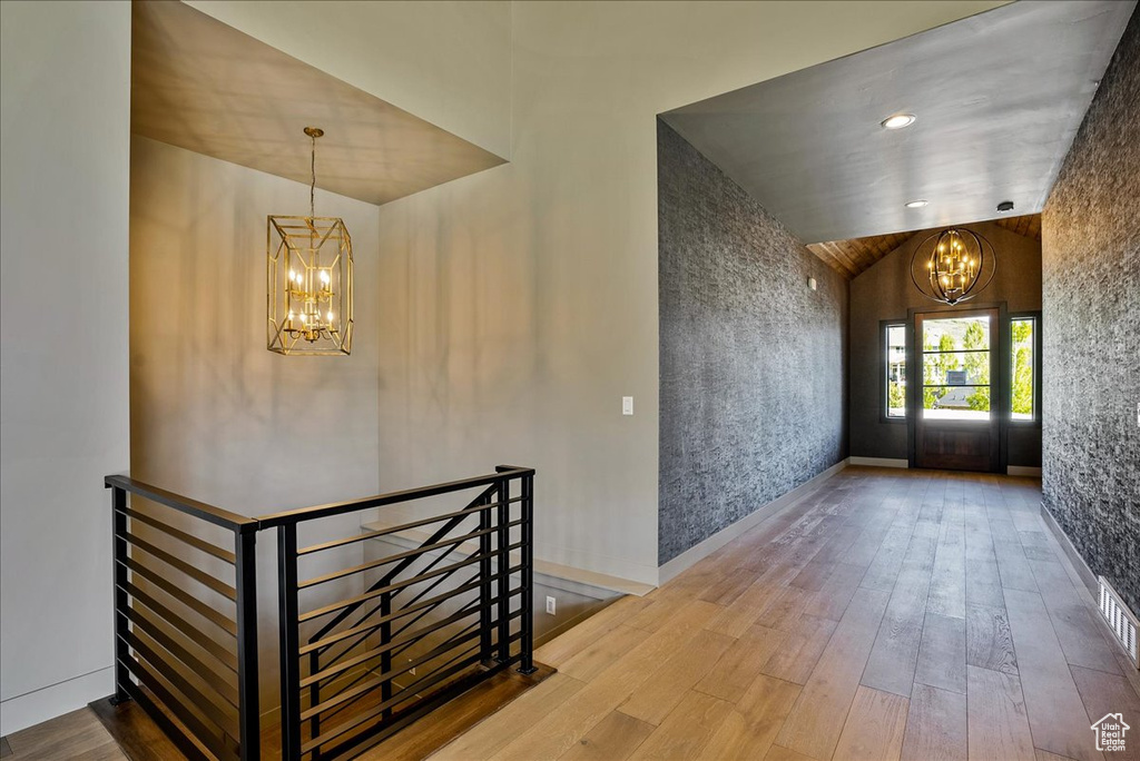 Interior space with lofted ceiling, a chandelier, and light hardwood / wood-style flooring