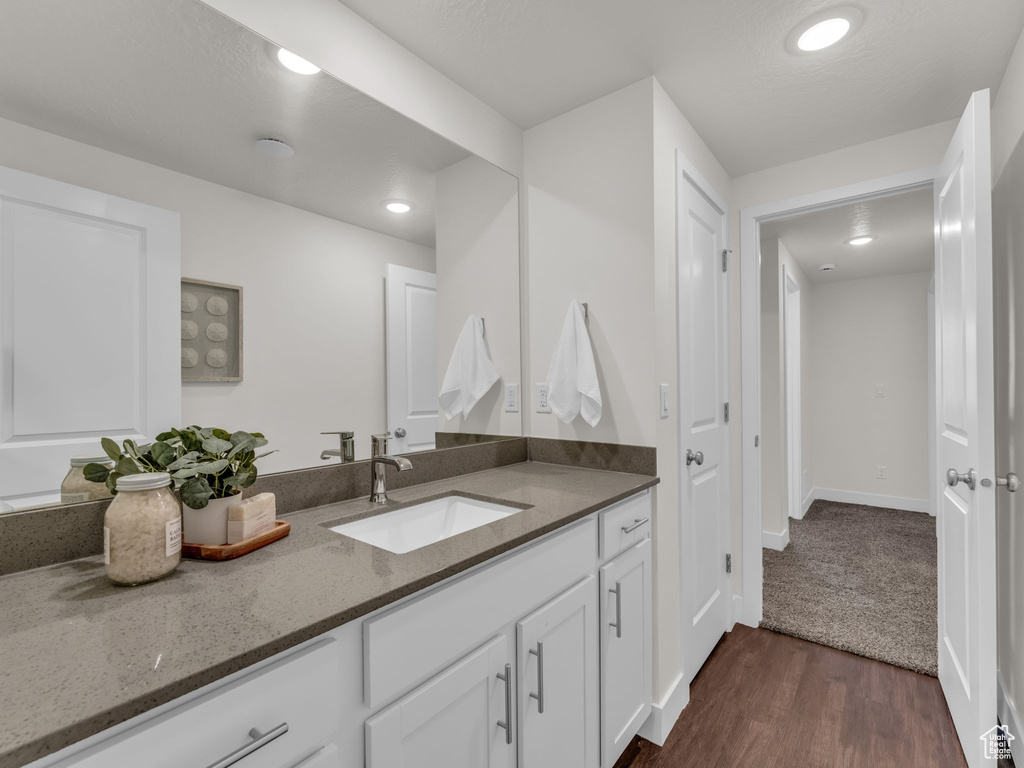 Bathroom with vanity, wood finished floors, recessed lighting, and baseboards