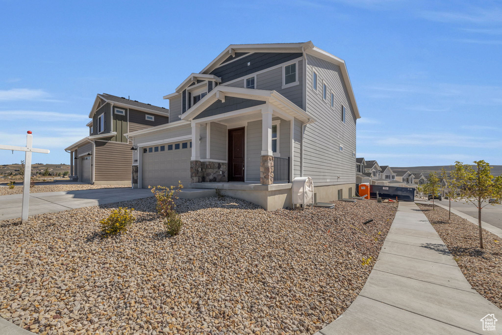 View of front of home featuring concrete driveway, a porch, and stone siding