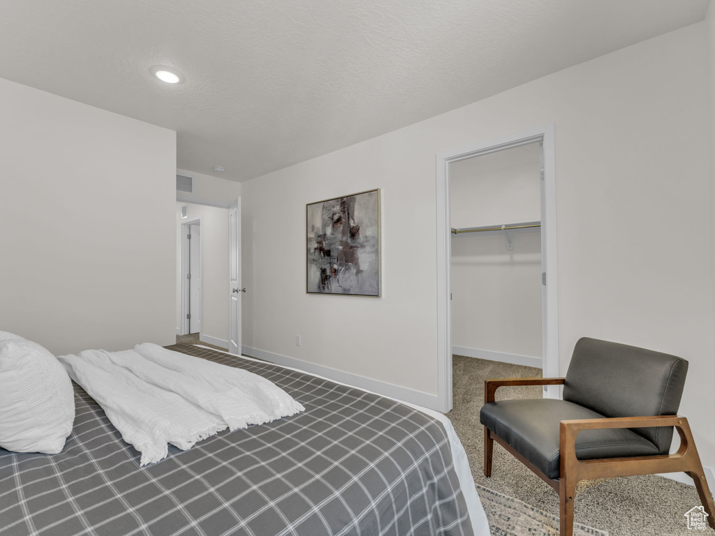 Carpeted bedroom with baseboards, a walk in closet, a closet, and recessed lighting