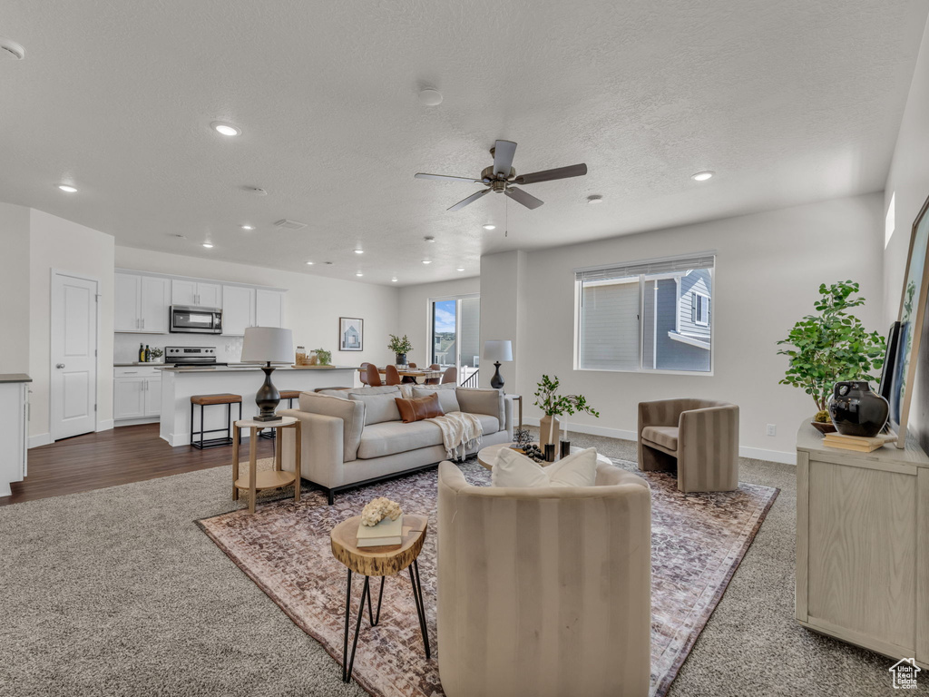 Living room with recessed lighting, baseboards, ceiling fan, dark colored carpet, and a textured ceiling