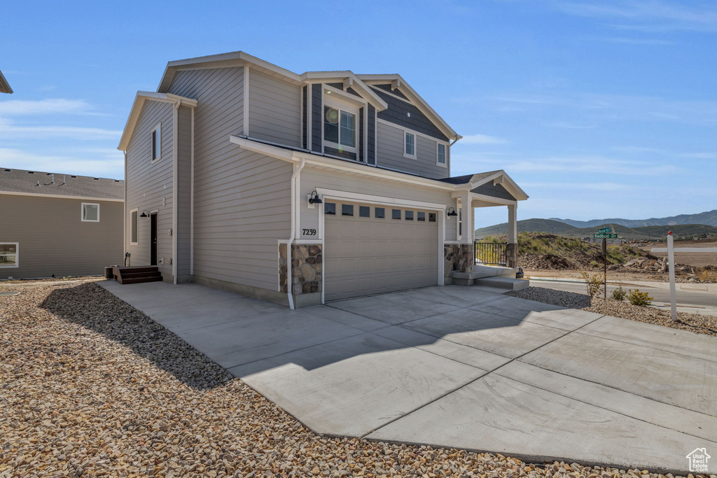 View of side of property with a mountain view, a garage, and driveway