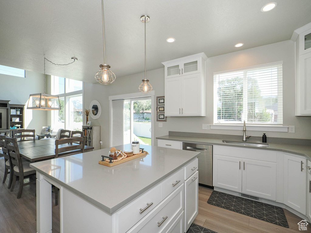 Kitchen featuring dark wood-type flooring, stainless steel dishwasher, sink, and white cabinets