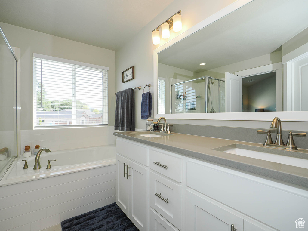 Bathroom featuring shower with separate bathtub and vanity