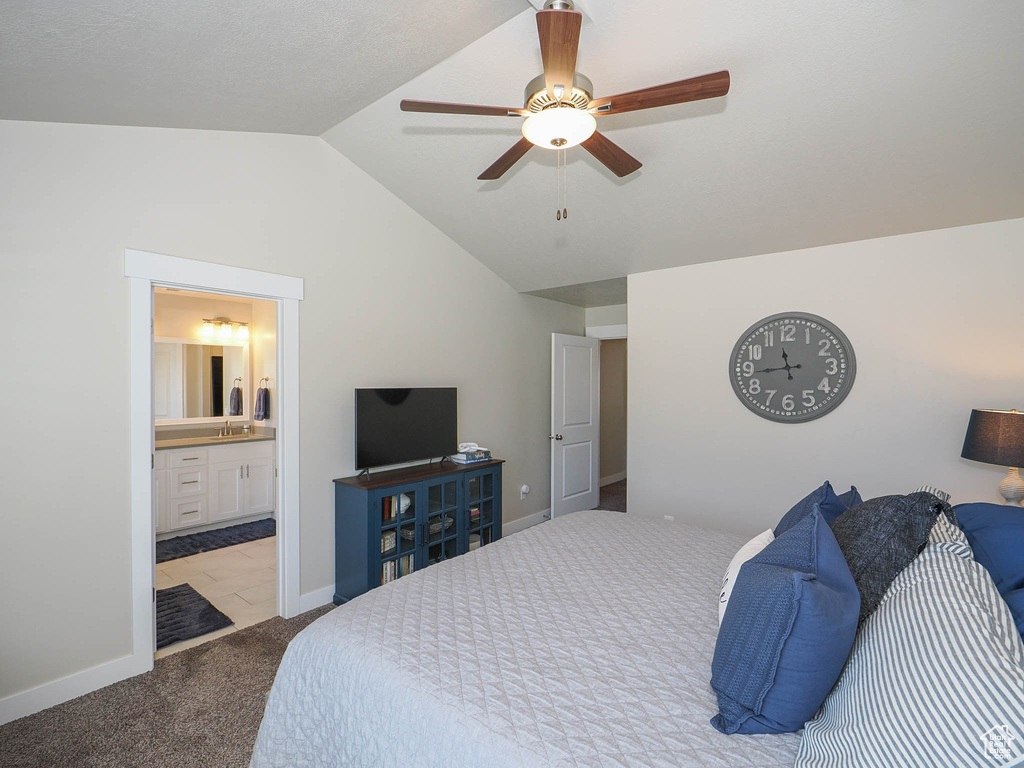 Carpeted bedroom featuring lofted ceiling, connected bathroom, and ceiling fan