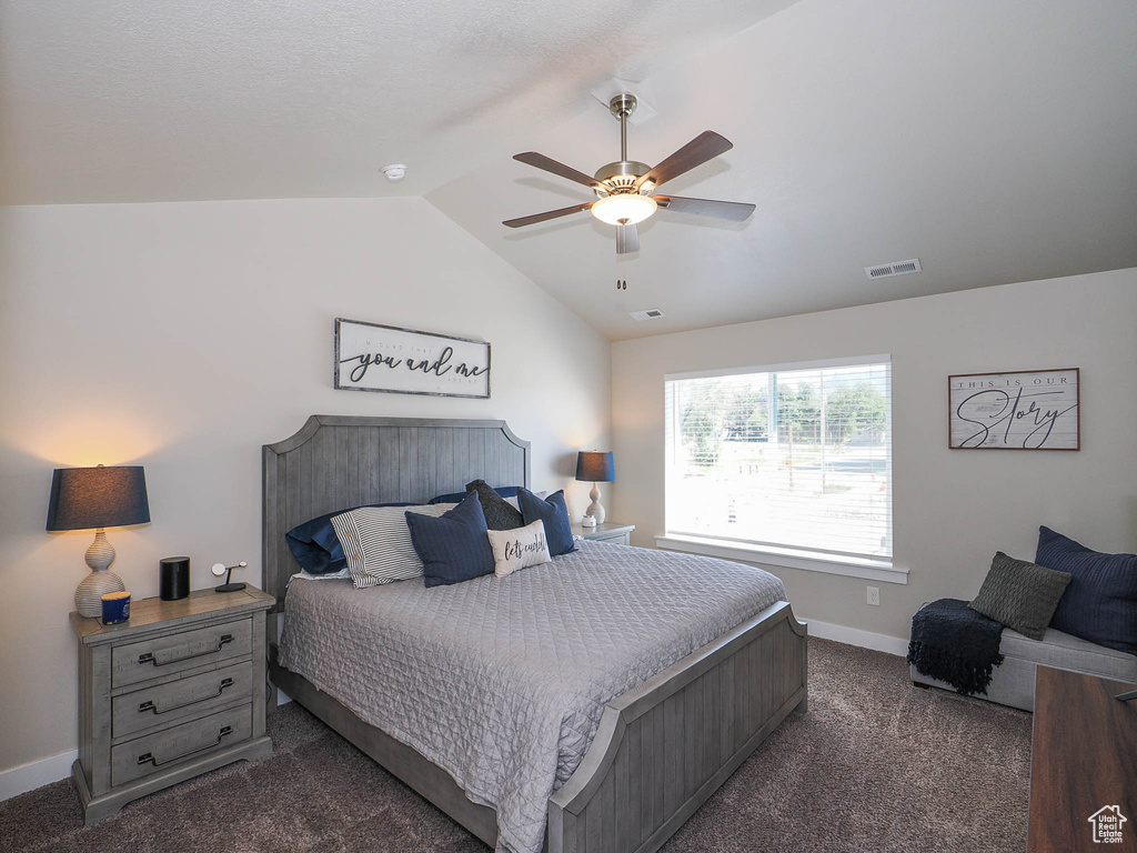 Carpeted bedroom featuring vaulted ceiling and ceiling fan