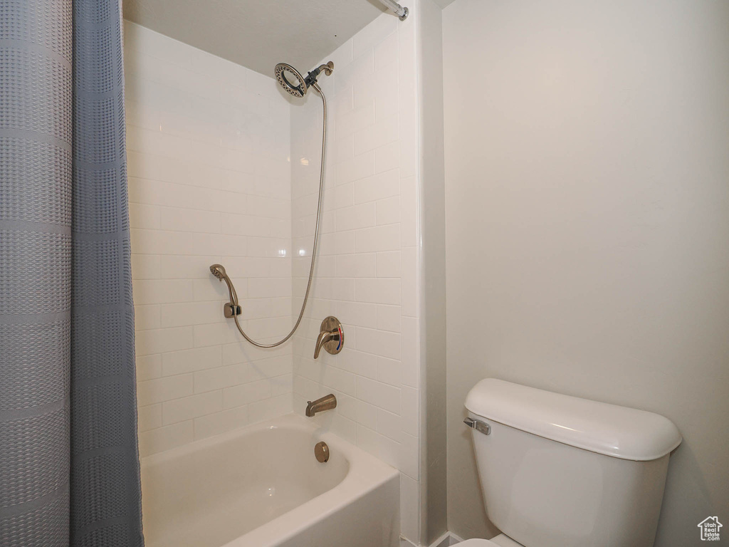 Bathroom featuring toilet and shower / bathtub combination with curtain