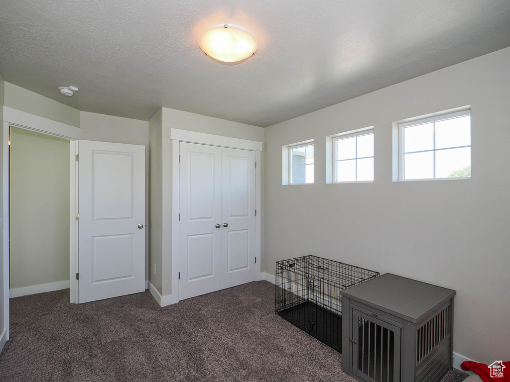 Bedroom with dark colored carpet and a closet