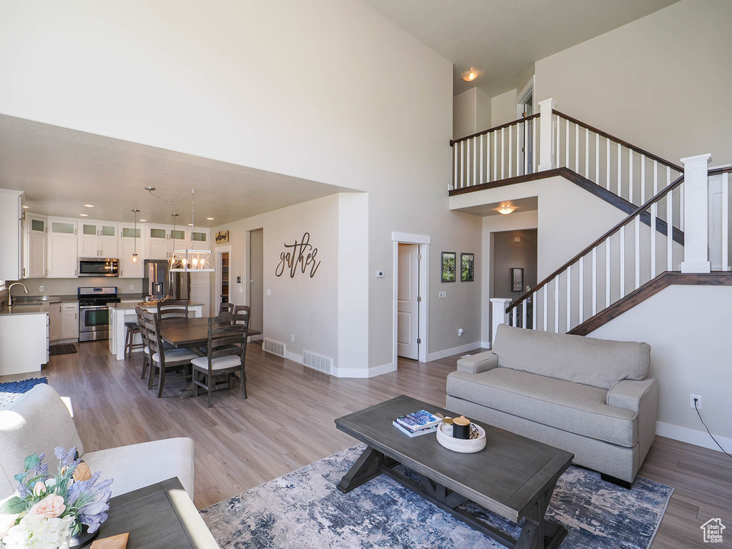 Living room featuring a high ceiling, light hardwood / wood-style floors, and sink