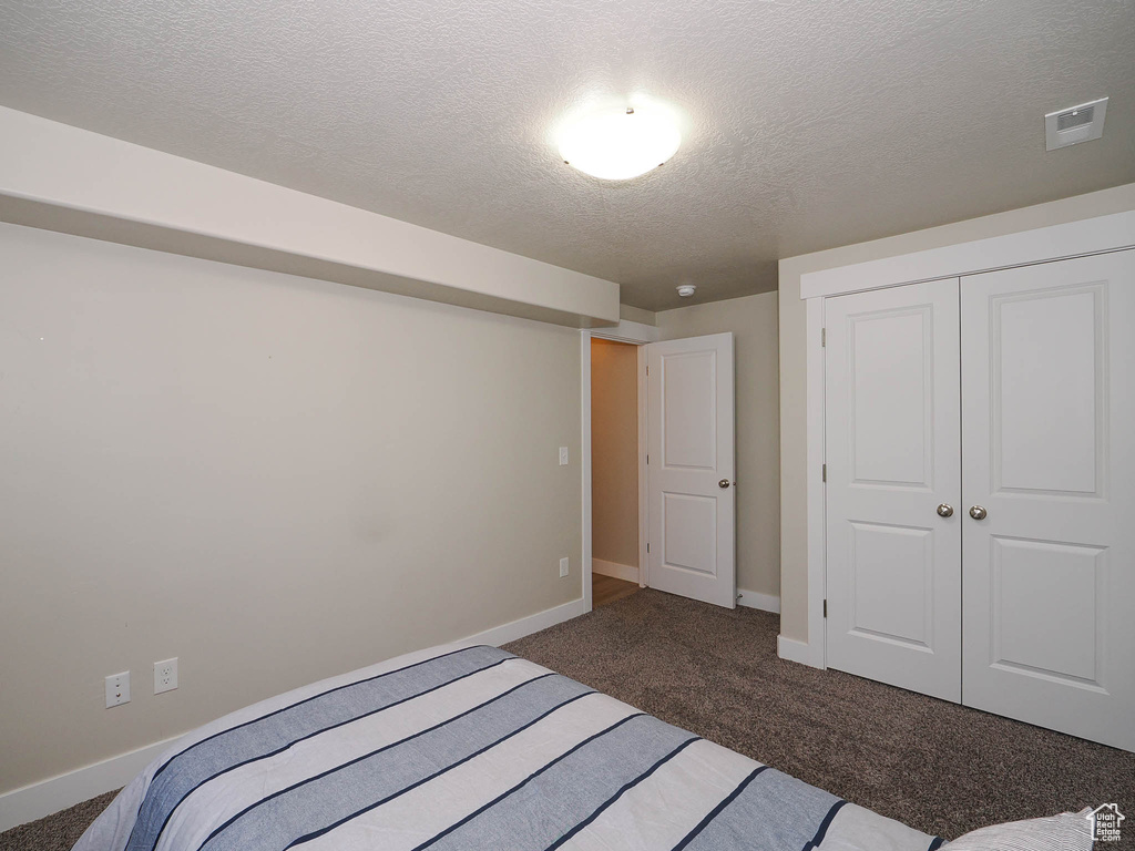 Carpeted bedroom with a closet and a textured ceiling