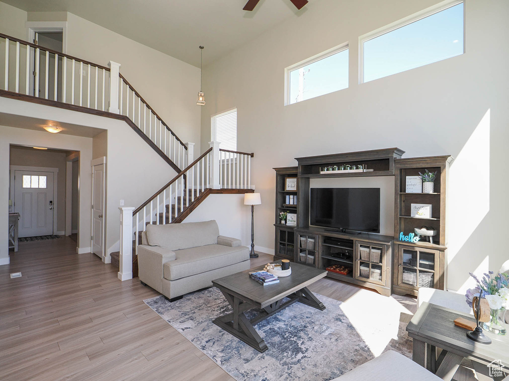 Living room with hardwood / wood-style floors, ceiling fan, and a high ceiling