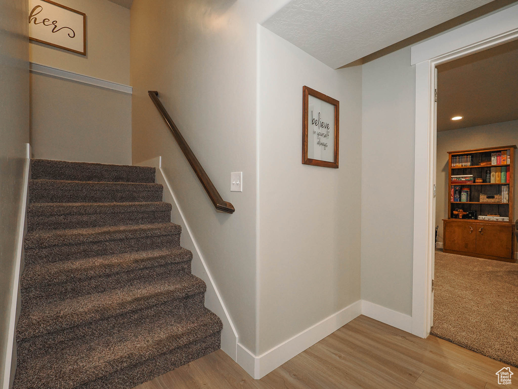 Stairs featuring a textured ceiling and carpet floors