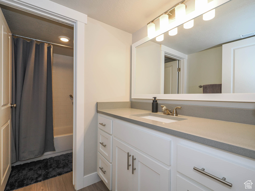 Bathroom with hardwood / wood-style flooring, shower / tub combo, and vanity