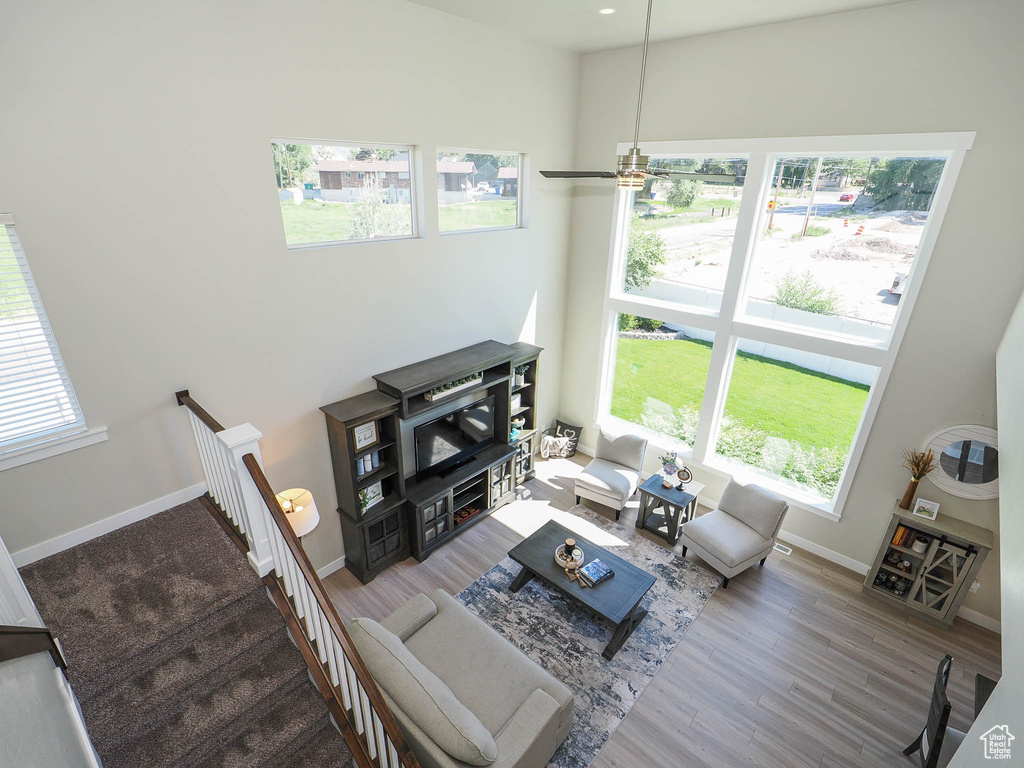 Living room with a high ceiling, ceiling fan, and hardwood / wood-style flooring