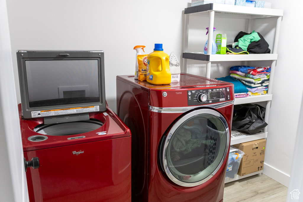 Laundry room featuring washing machine and clothes dryer and light hardwood / wood-style flooring