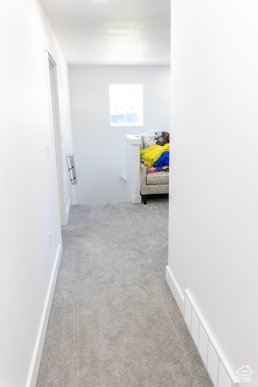 Corridor featuring light colored carpet