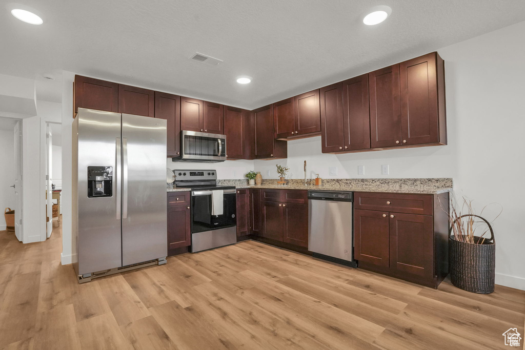 Kitchen featuring appliances with stainless steel finishes, light hardwood / wood-style flooring, sink, and dark brown cabinetry