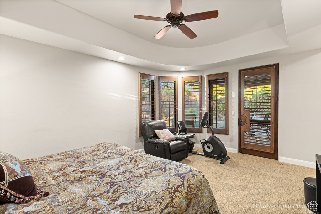 Carpeted bedroom with access to exterior, ceiling fan, and a tray ceiling