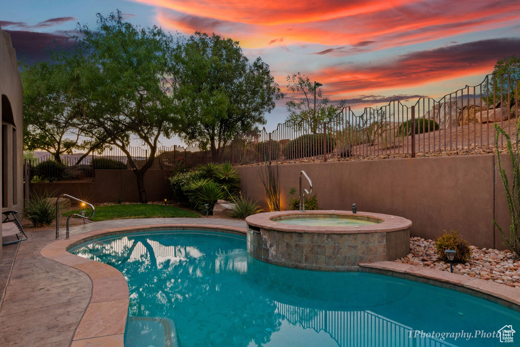 Pool at dusk with an in ground hot tub