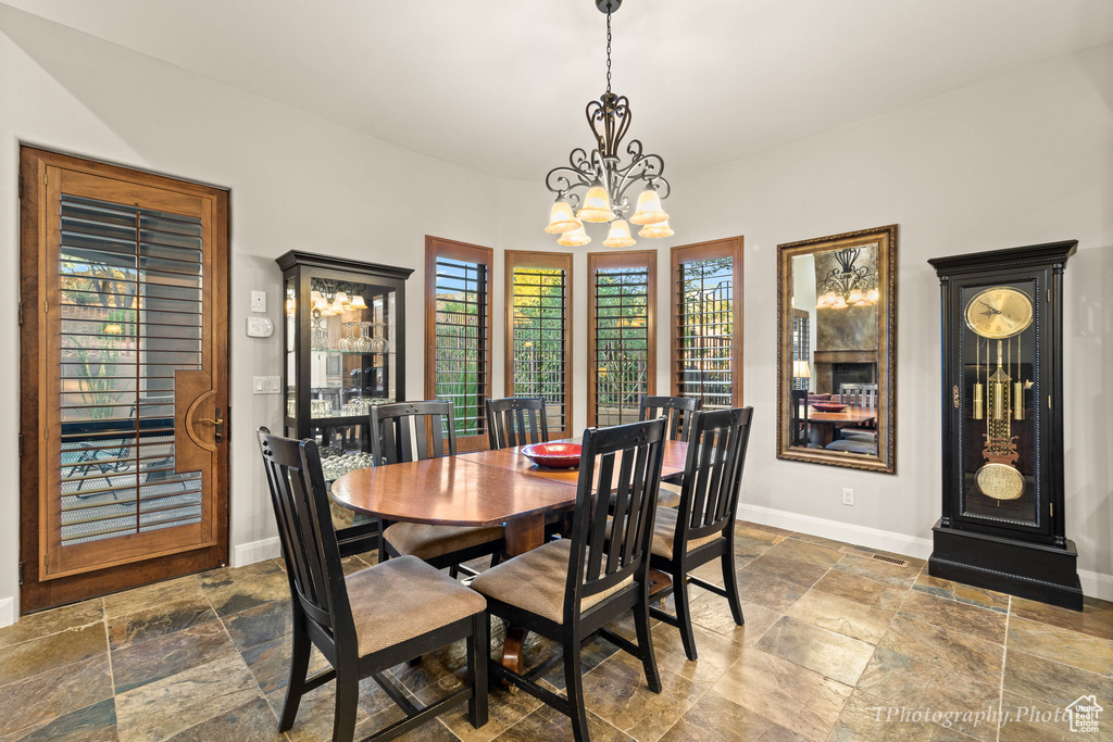 Dining space with dark tile patterned flooring, plenty of natural light, and an inviting chandelier