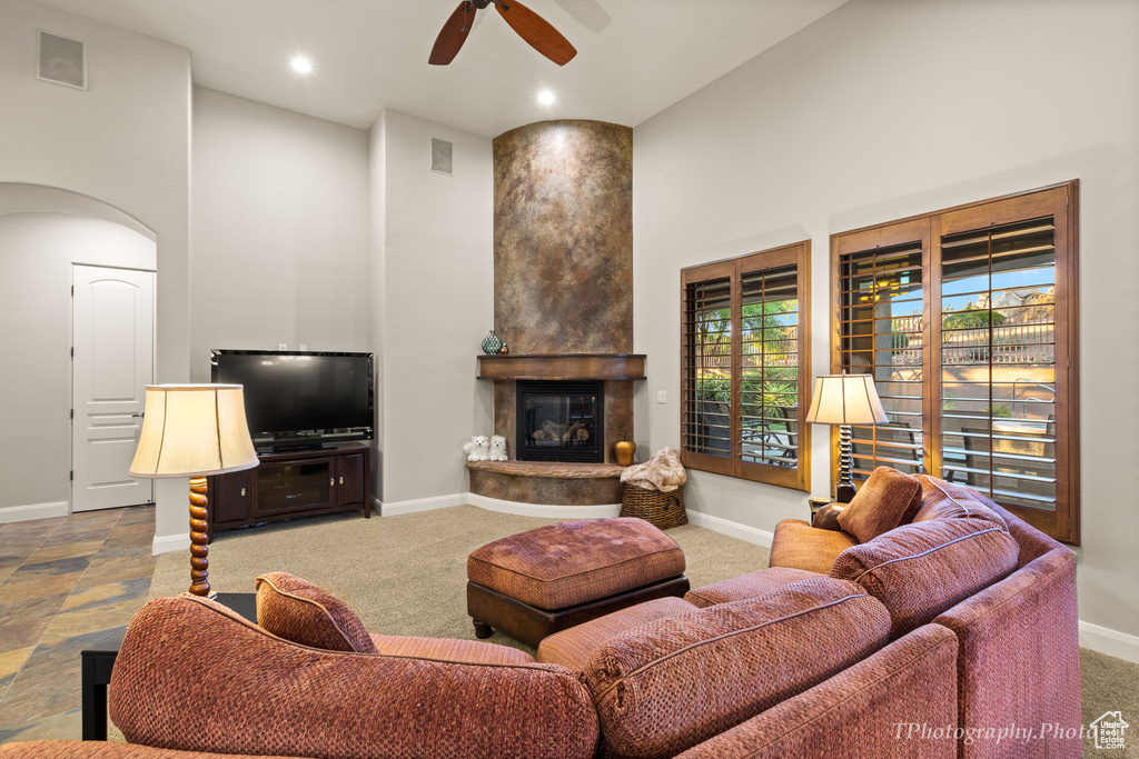 Carpeted living room with ceiling fan and a fireplace