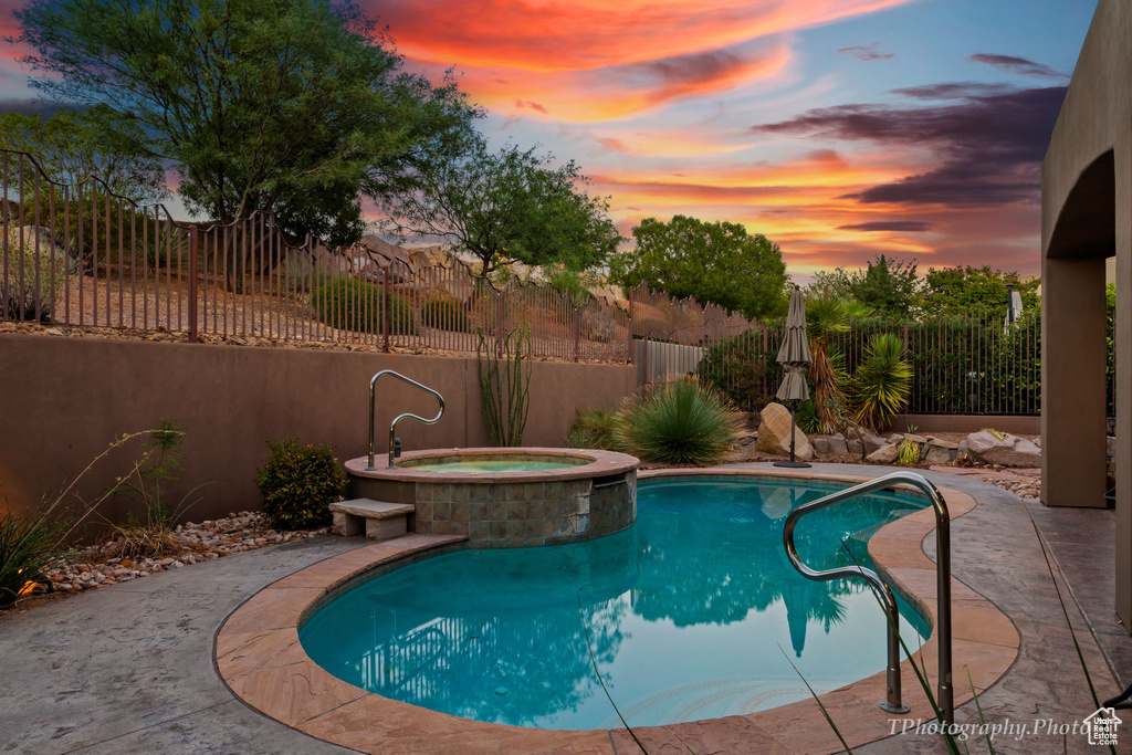 Pool at dusk with an in ground hot tub