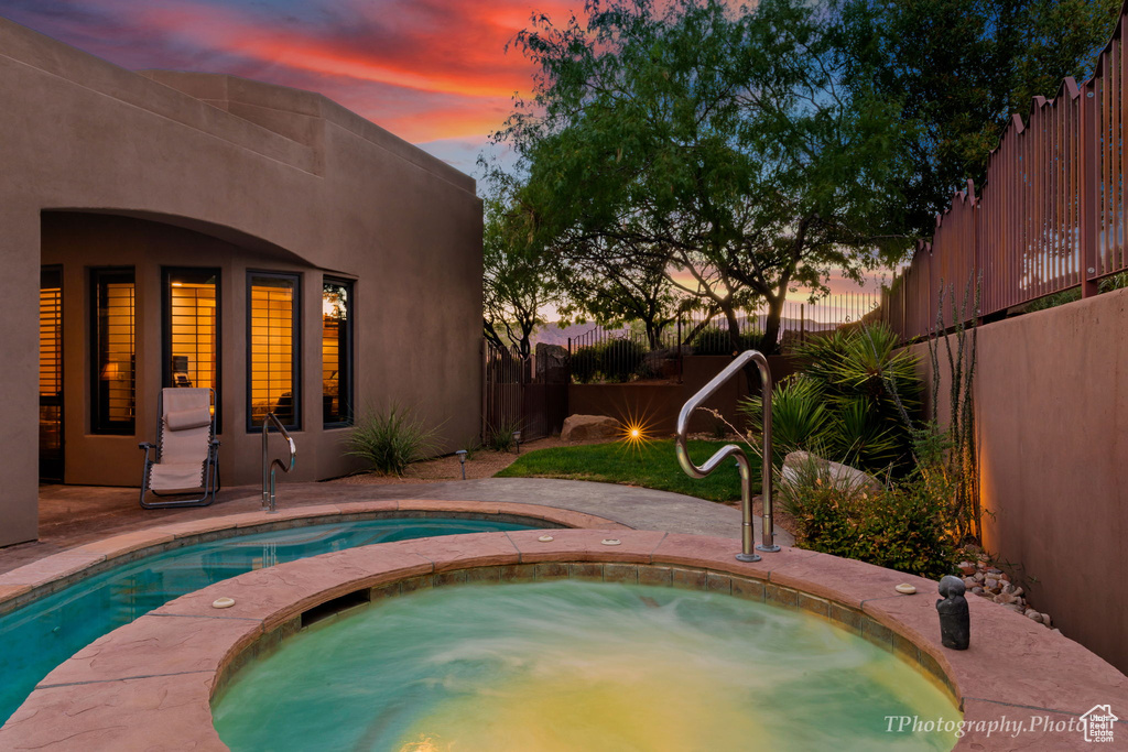 Pool at dusk with an in ground hot tub