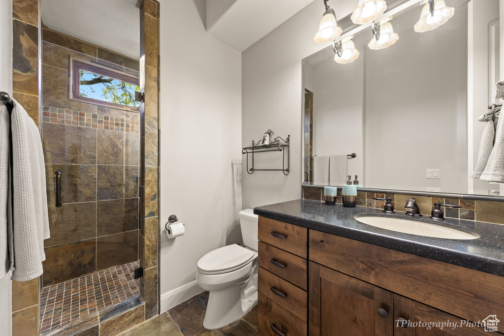 Bathroom with tiled shower, vanity, toilet, and tile patterned floors