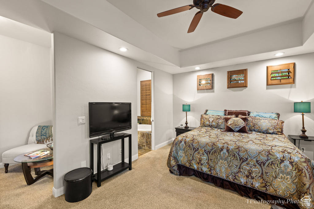 Carpeted bedroom with connected bathroom and ceiling fan