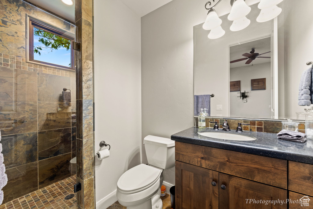 Bathroom with vanity, toilet, an enclosed shower, and ceiling fan