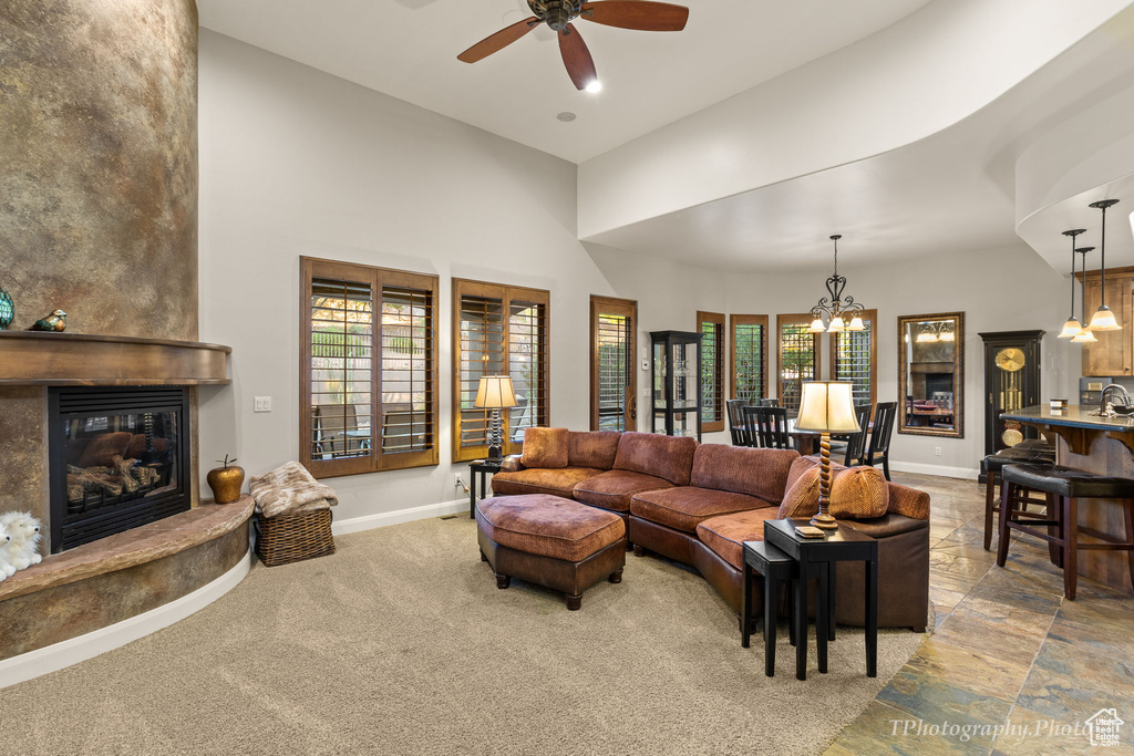 Living room with plenty of natural light, ceiling fan with notable chandelier, carpet floors, and a fireplace