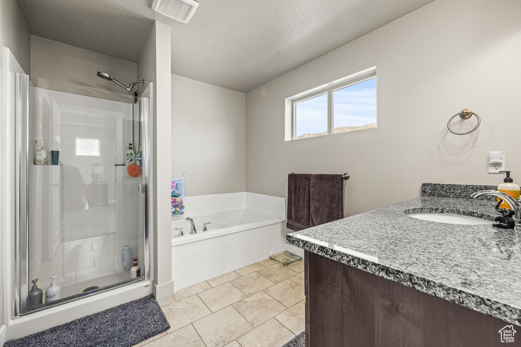 Bathroom with vanity, a textured ceiling, separate shower and tub, and tile patterned floors