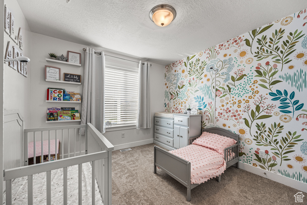 Carpeted bedroom with a nursery area and a textured ceiling