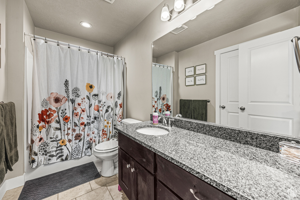 Bathroom with tile patterned flooring, vanity, toilet, and walk in shower