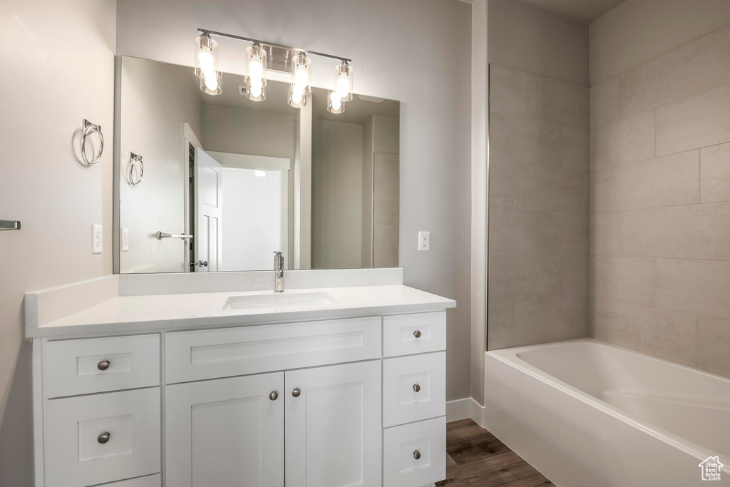 Bathroom featuring tiled shower / bath, vanity, and wood-type flooring