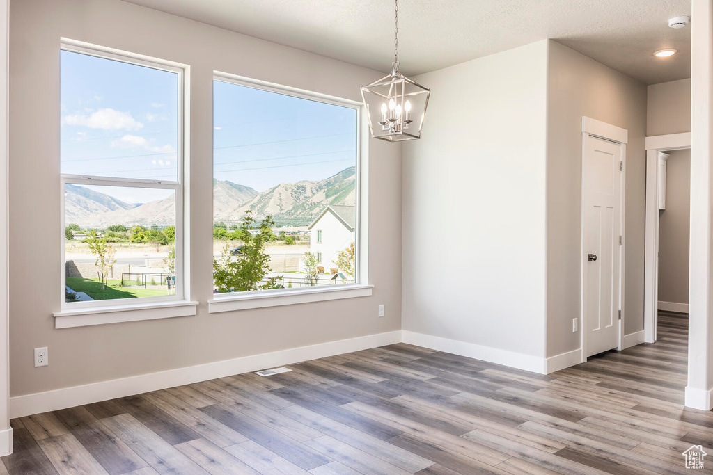 Spare room featuring a mountain view, a notable chandelier, and hardwood / wood-style flooring