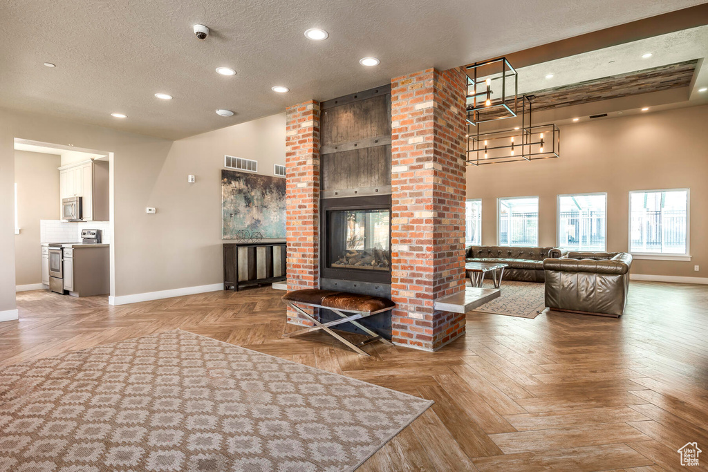 Unfurnished living room with a fireplace, parquet flooring, a textured ceiling, and brick wall