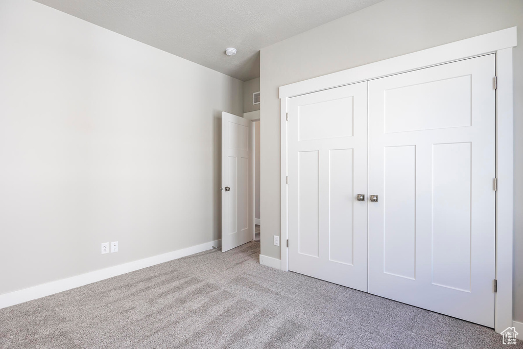 Unfurnished bedroom with light colored carpet and a closet