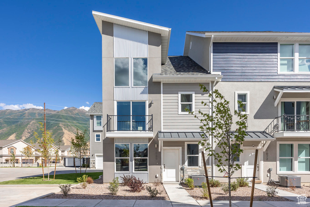 View of front of home with a balcony, a mountain view, and central air condition unit