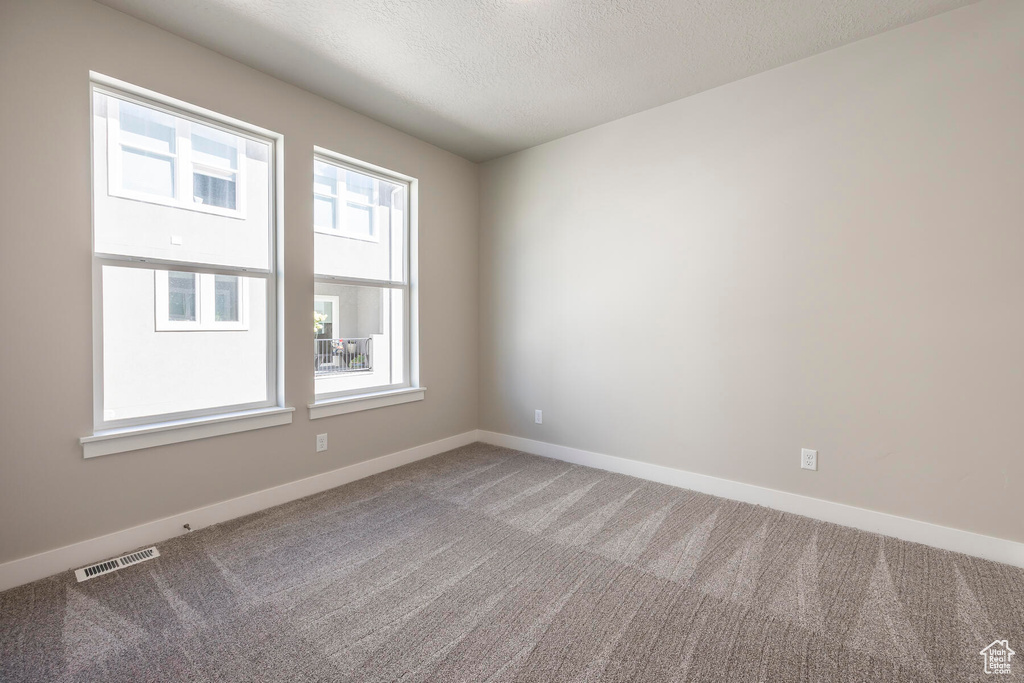 Spare room featuring a textured ceiling and carpet