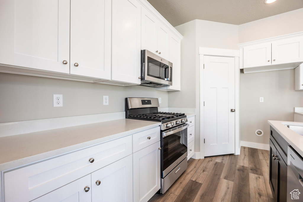 Kitchen with light wood-type flooring, appliances with stainless steel finishes, and white cabinetry