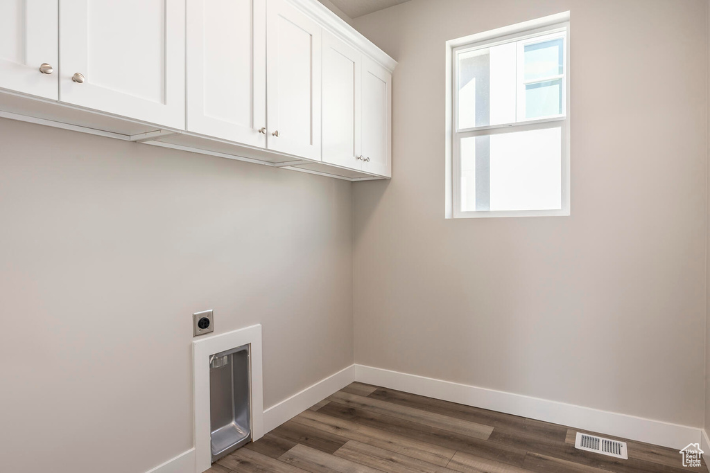 Laundry room featuring dark wood-type flooring, hookup for an electric dryer, and cabinets