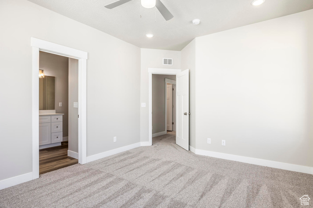 Unfurnished bedroom featuring ceiling fan, connected bathroom, and light carpet