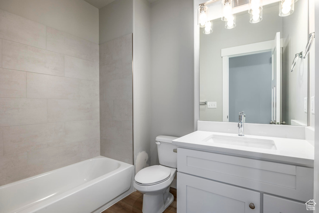 Full bathroom featuring vanity, toilet, tiled shower / bath combo, and hardwood / wood-style floors