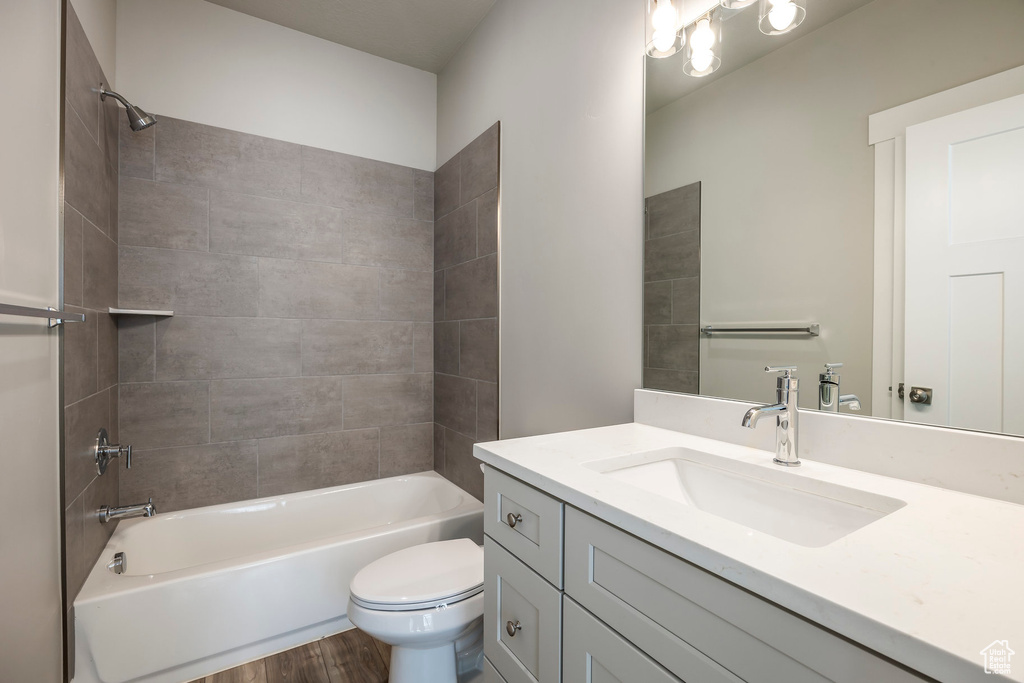 Full bathroom featuring hardwood / wood-style floors, tiled shower / bath, toilet, and vanity