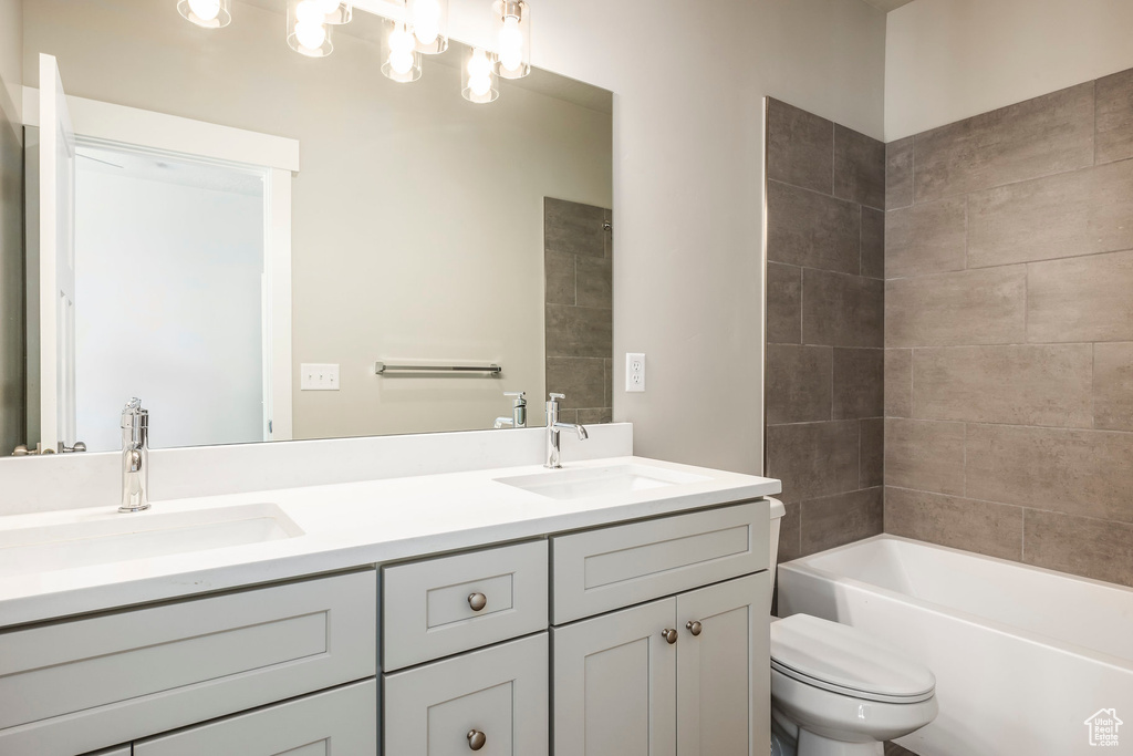 Full bathroom with toilet, tiled shower / bath combo, and vanity