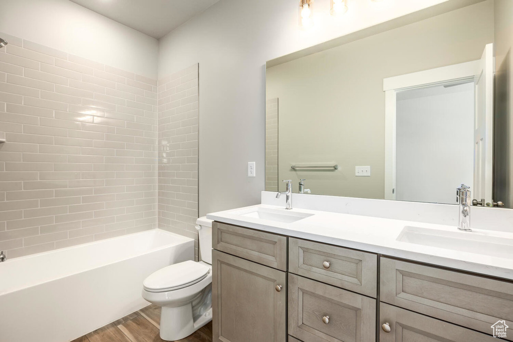 Full bathroom featuring tiled shower / bath, vanity, toilet, and hardwood / wood-style flooring