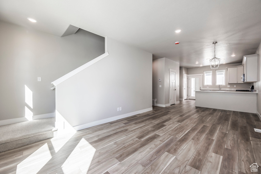 Unfurnished living room with an inviting chandelier and hardwood / wood-style flooring